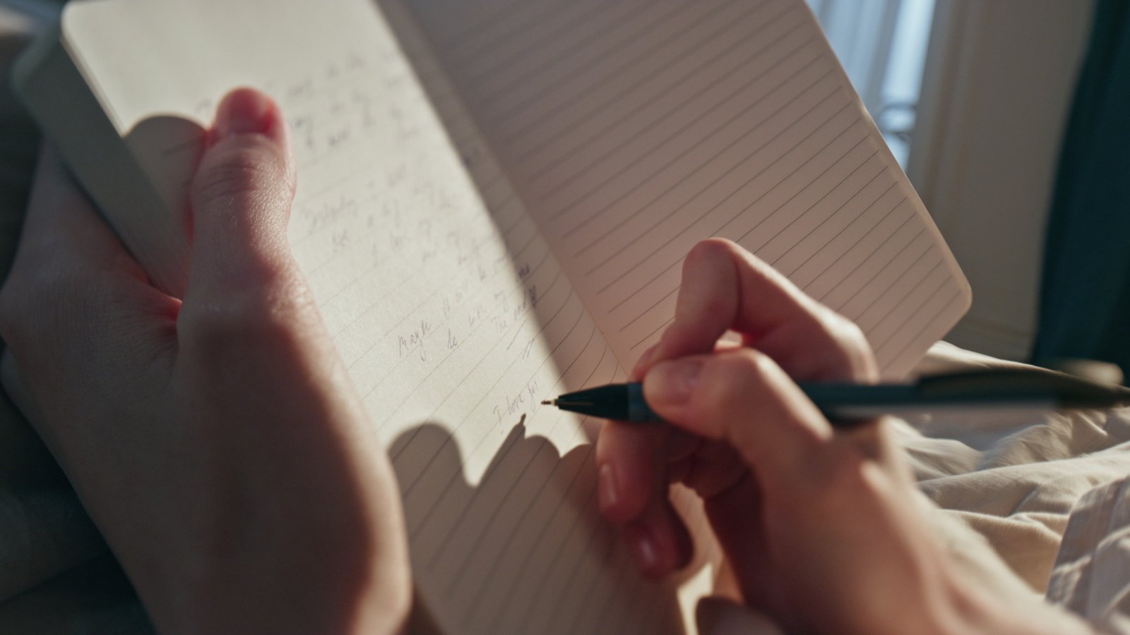 Hand schreibt in ein aufgeschlagenes Tagebuch