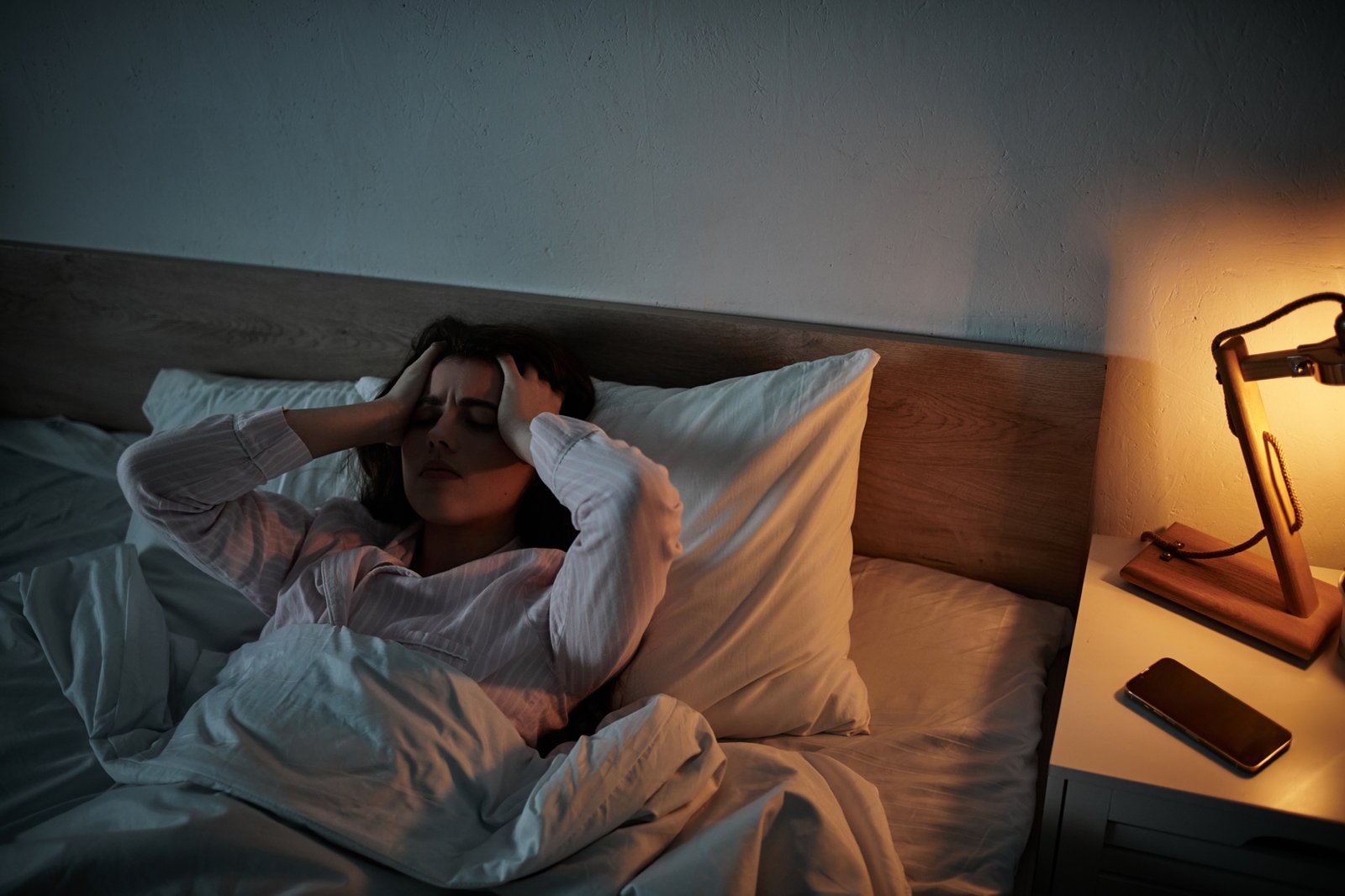 Person liegt schlaflos im Bett und schaut zur Decke